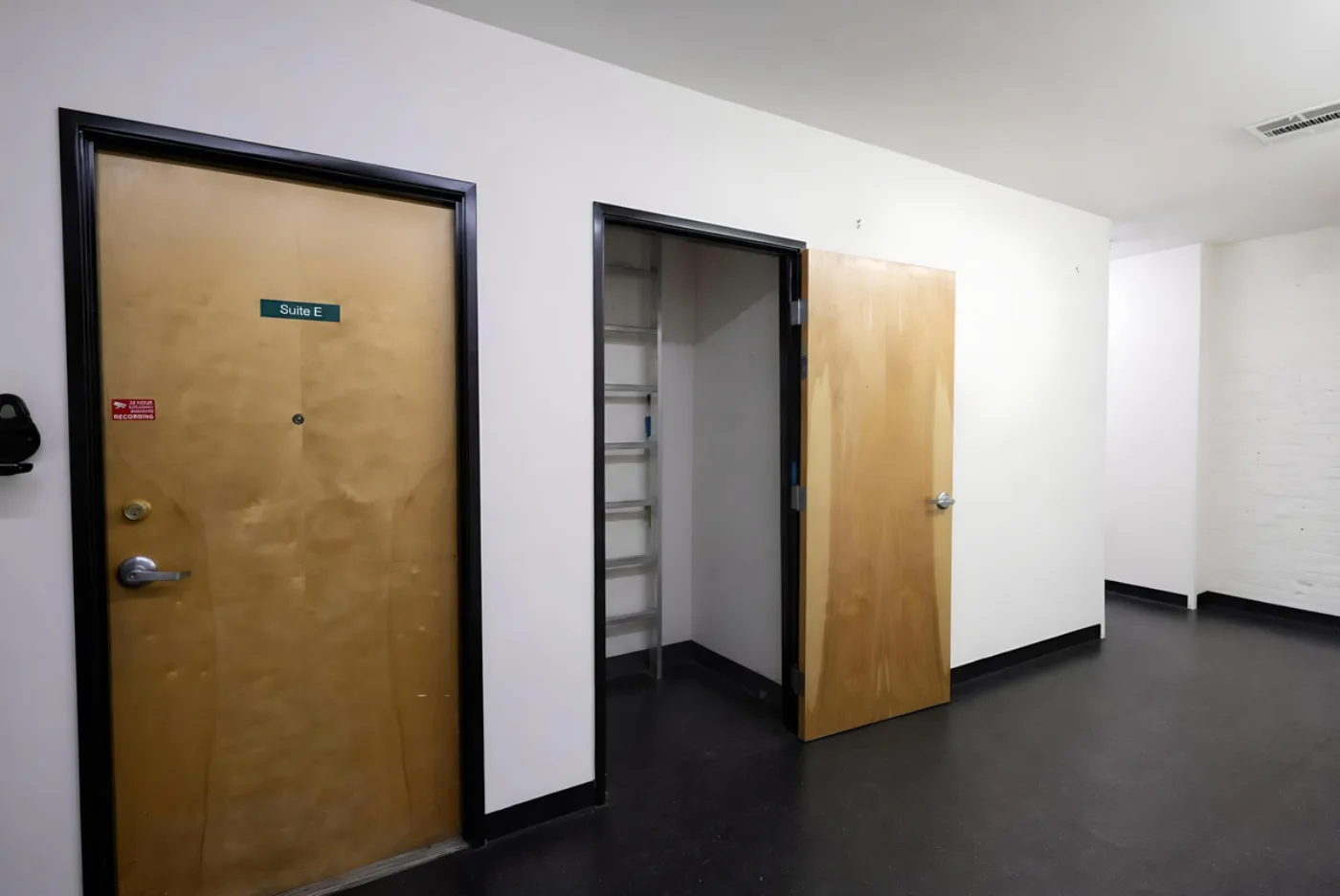 Corridor with Suite E and a storage closet